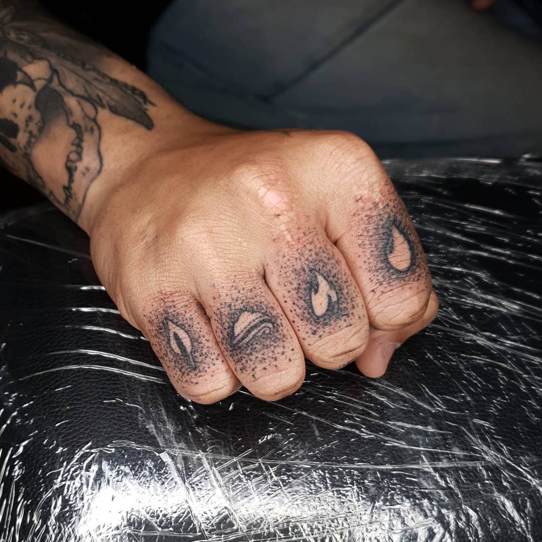 A hand with 4 elements tattoos on each finger